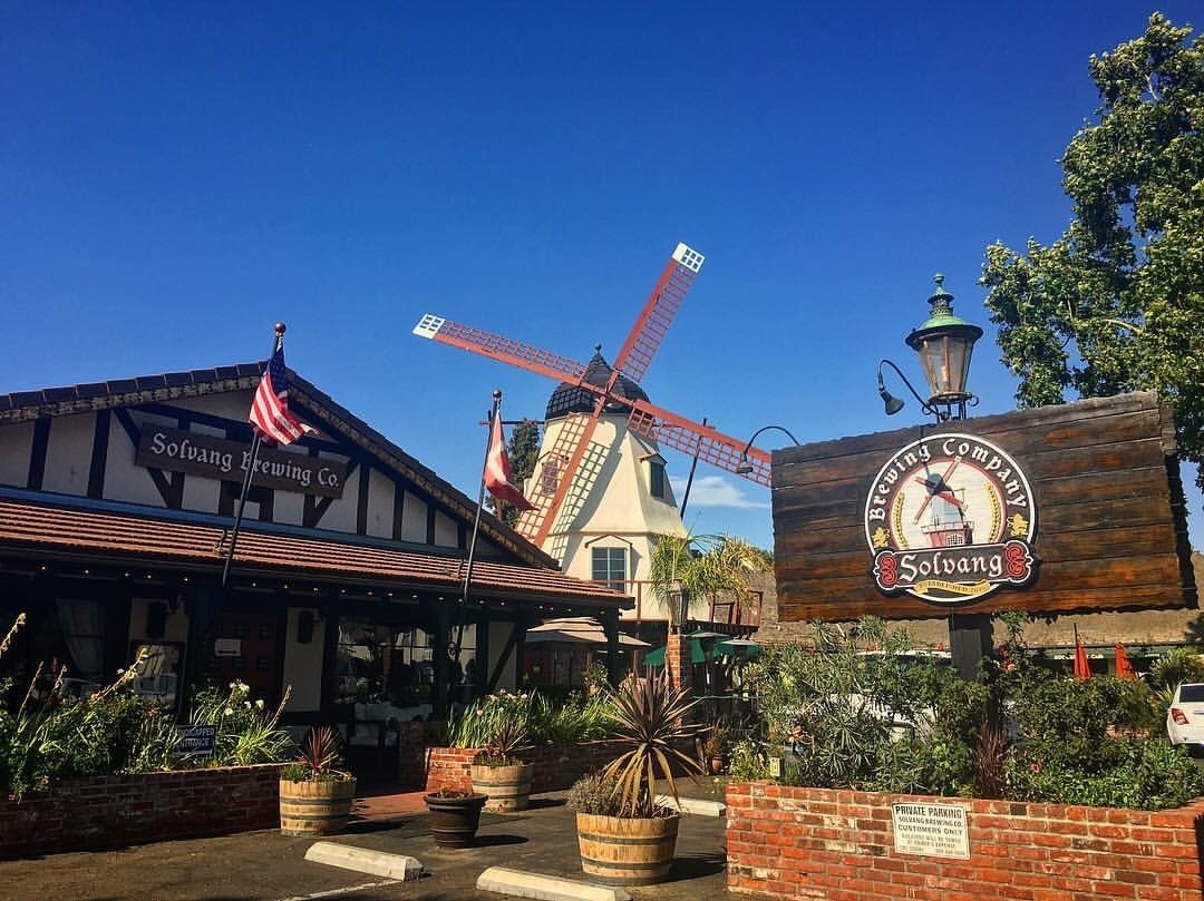 The iconic windmill exterior of Solvang Brewing Company with outdoor seating in view.