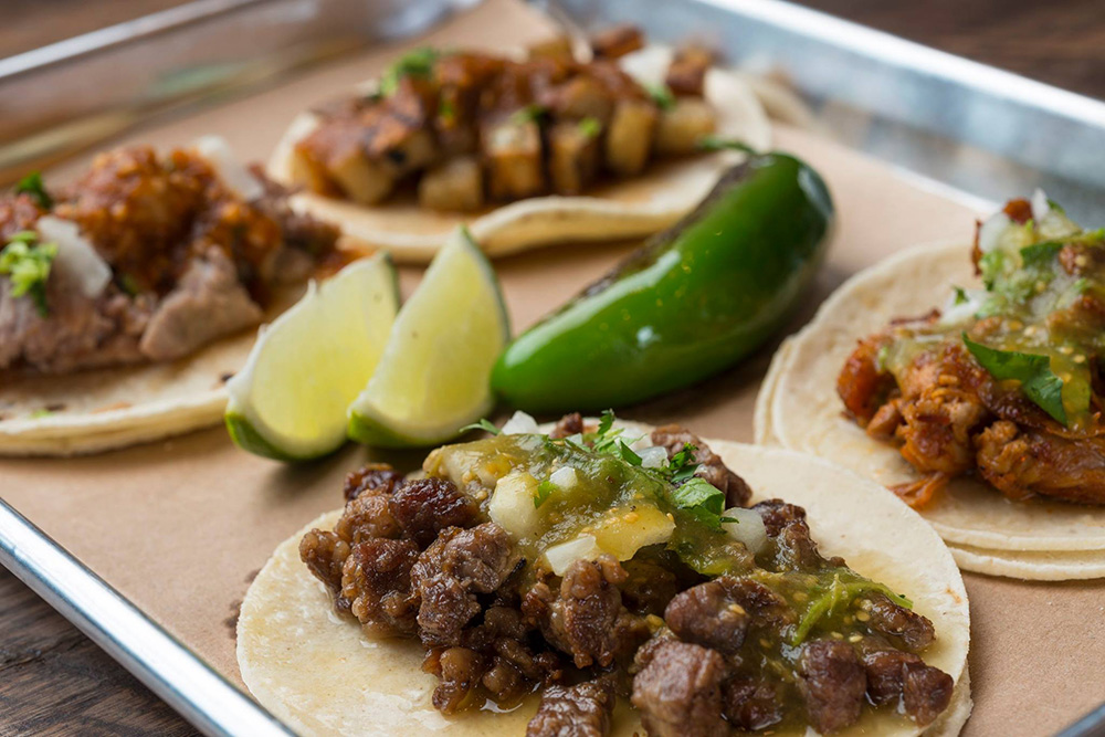 Street-style tacos on a plate with lime wedges