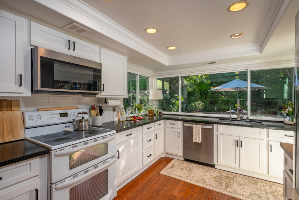 Updated kitchen with ample counter space, modern cabinetry, and large windows overlooking the outdoor greenery. Bright, functional layout designed for both everyday cooking and hosting.