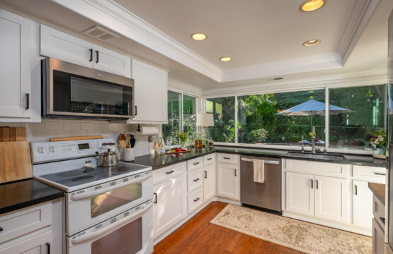 Updated kitchen with ample counter space, modern cabinetry, and large windows overlooking the outdoor greenery. Bright, functional layout designed for both everyday cooking and hosting.