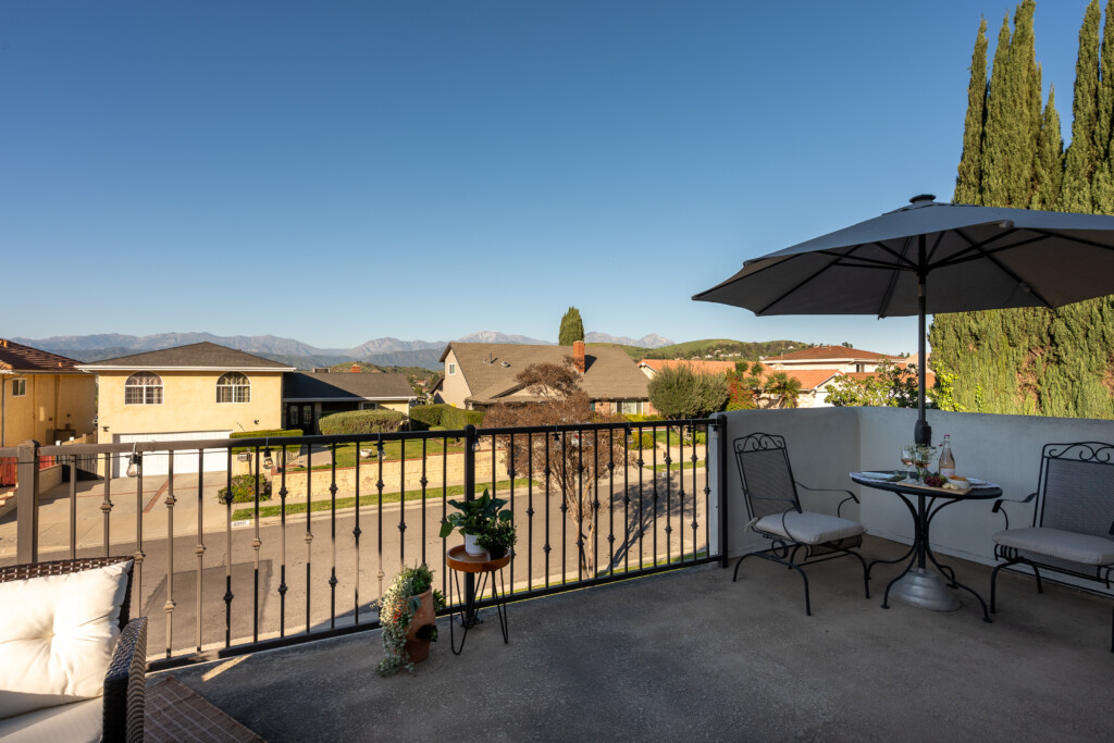 Private outdoor balcony with comfortable seating and open neighborhood and mountain views. A perfect spot for morning coffee, sunset unwinding, or casual outdoor dining.