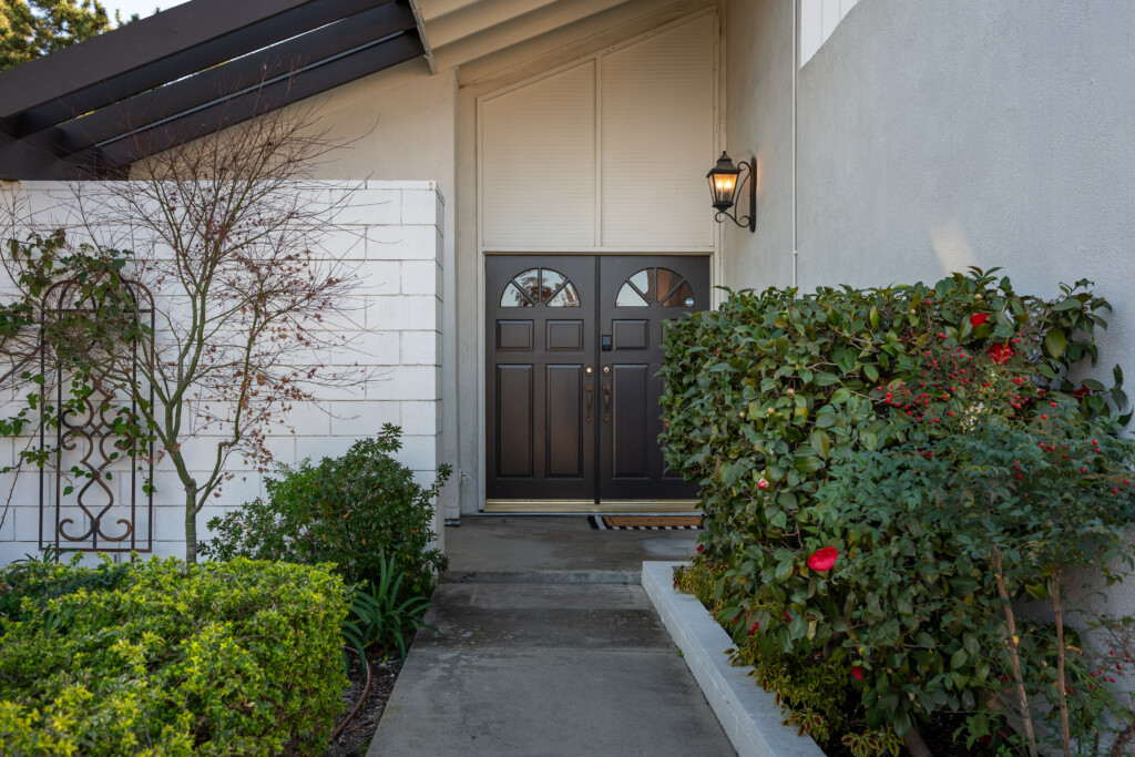 Inviting front entry with elegant double doors, warm exterior lighting, and well-maintained greenery creating a welcoming first impression and polished curb appeal.