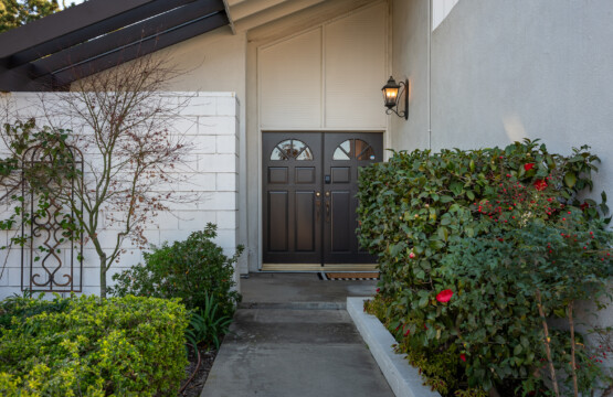 Inviting front entry with elegant double doors, warm exterior lighting, and well-maintained greenery creating a welcoming first impression and polished curb appeal.