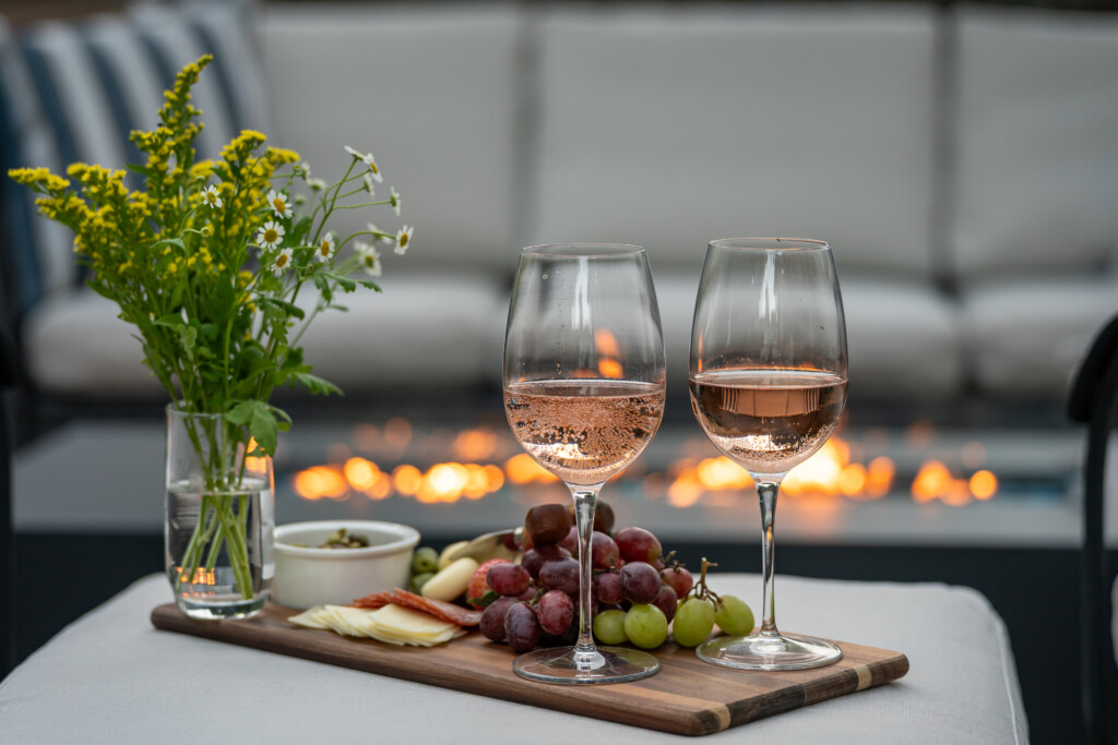 Cozy fireside wine and charcuterie setup creating a warm, romantic outdoor evening ambiance.