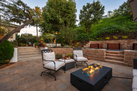 Beautifully designed outdoor living space with fire feature, lounge seating, and layered landscaping creating a warm, private setting for relaxing evenings or entertaining.