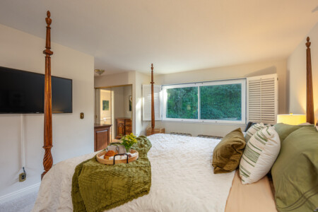 Comfortable primary bedroom with a statement four-poster bed, soft natural light, and TV for relaxed evenings in. A restful space designed for slow mornings and easy wind-down routines.