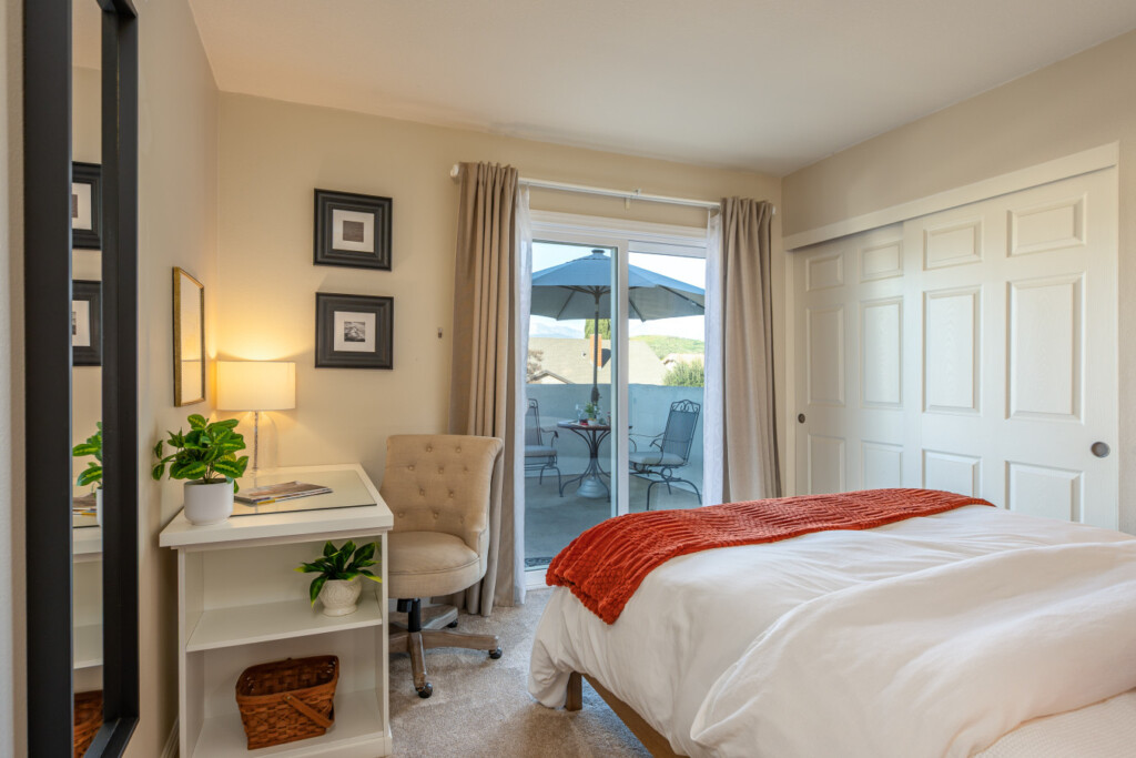 Comfortable bedroom with a dedicated desk and sliding door access to a private balcony seating area. A bright, peaceful space for work, rest, and fresh-air breaks throughout the day.