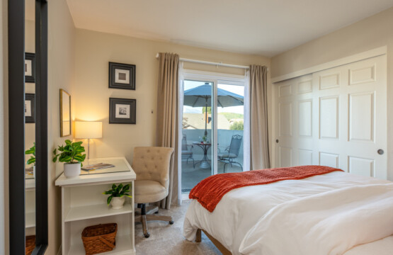 Comfortable bedroom with a dedicated desk and sliding door access to a private balcony seating area. A bright, peaceful space for work, rest, and fresh-air breaks throughout the day.