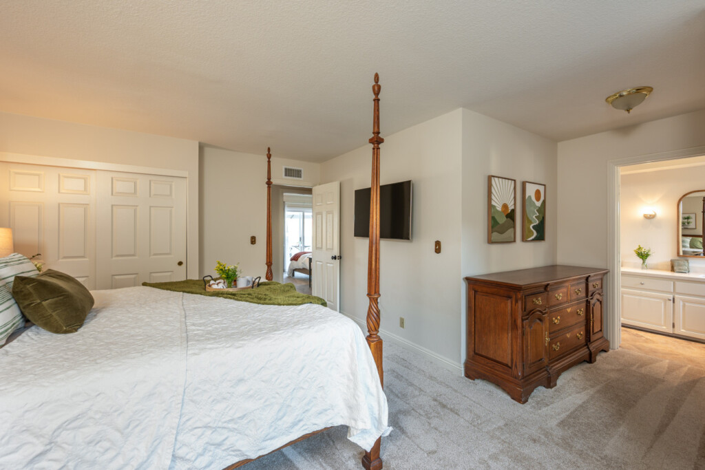 Spacious bedroom with a classic four-poster bed, TV, and easy access to the ensuite bath for added convenience. Designed to support comfortable, settled-in living for extended stays.