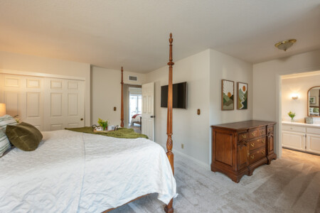 Spacious bedroom with a classic four-poster bed, TV, and easy access to the ensuite bath for added convenience. Designed to support comfortable, settled-in living for extended stays.