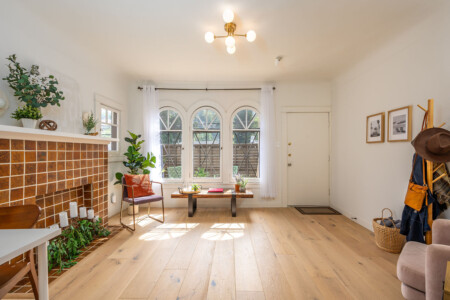 Sunlight pours through arched windows into this inviting living space, highlighting the home’s original charm and warm finishes. A peaceful spot to unwind, with a connection to the courtyard just beyond.