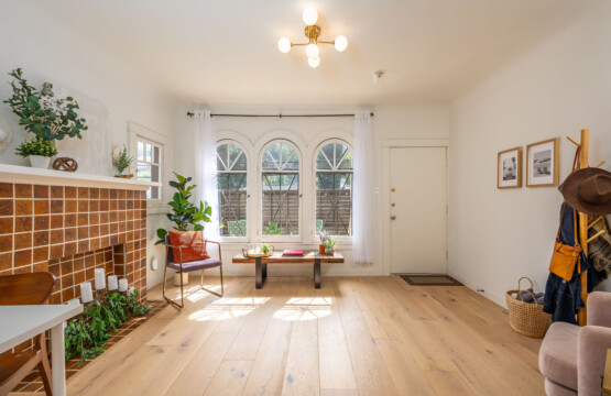 Sunlight pours through arched windows into this inviting living space, highlighting the home’s original charm and warm finishes. A peaceful spot to unwind, with a connection to the courtyard just beyond.