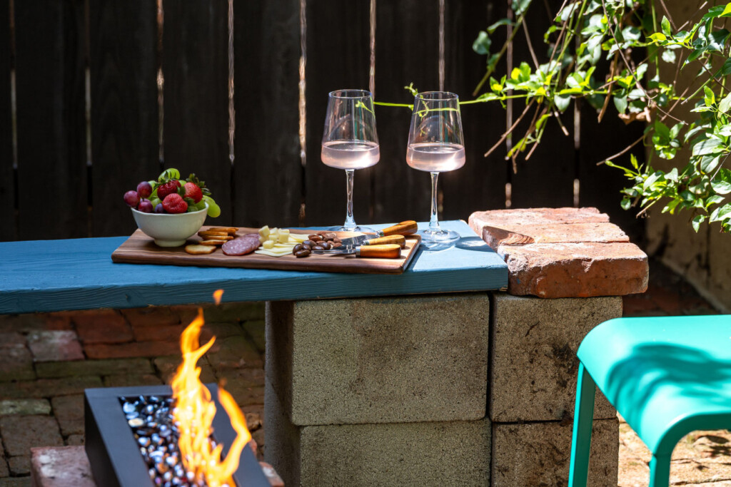 A private brick courtyard with a built-in fire pit, perfect for relaxed evenings under the string lights. Surrounded by greenery, it’s an inviting outdoor space that feels like your own hidden retreat.