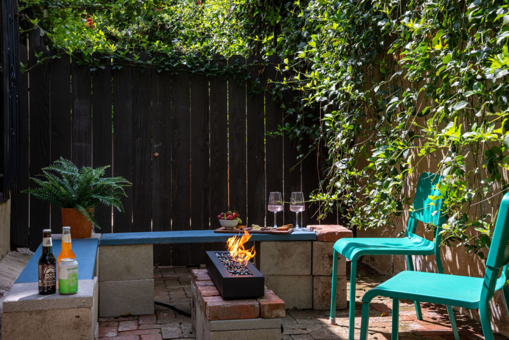 A private brick courtyard with a built-in fire pit, perfect for relaxed evenings under the string lights. Surrounded by greenery, it’s an inviting outdoor space that feels like your own hidden retreat.