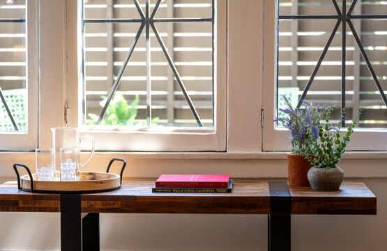A sunlit corner framed by original arched windows, offering a quiet place to read or unwind. With leafy views and soft light, it’s a peaceful spot to settle into the rhythm of the neighborhood.