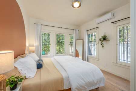 A light-filled bedroom with leafy views from every window, creating a calm and airy retreat. With space to unwind and settle in, it’s ideal for longer, comfortable stays.