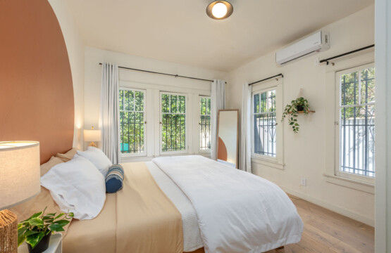 A light-filled bedroom with leafy views from every window, creating a calm and airy retreat. With space to unwind and settle in, it’s ideal for longer, comfortable stays.