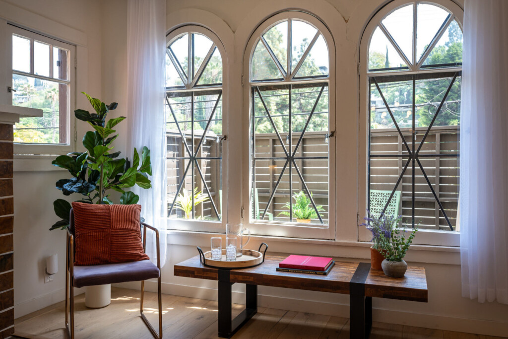A sunlit corner framed by original arched windows, offering a quiet place to read or unwind. With leafy views and soft light, it’s a peaceful spot to settle into the rhythm of the neighborhood.