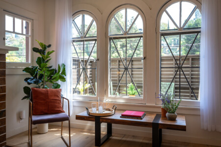 A sunlit corner framed by original arched windows, offering a quiet place to read or unwind. With leafy views and soft light, it’s a peaceful spot to settle into the rhythm of the neighborhood.