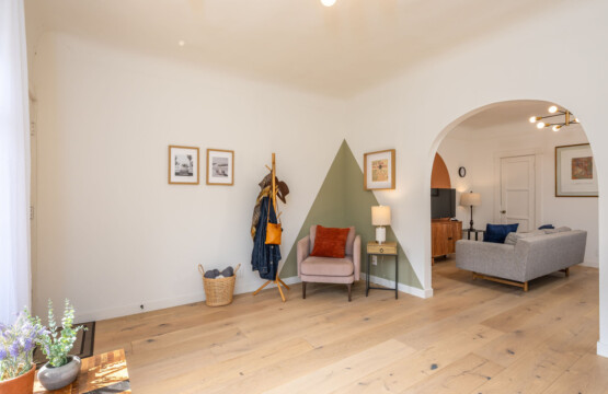 A quiet corner with room to settle in, featuring a cozy reading chair and thoughtful touches throughout. Just beyond the archway, the home opens up, offering both privacy and an easy, connected flow for daily living.
